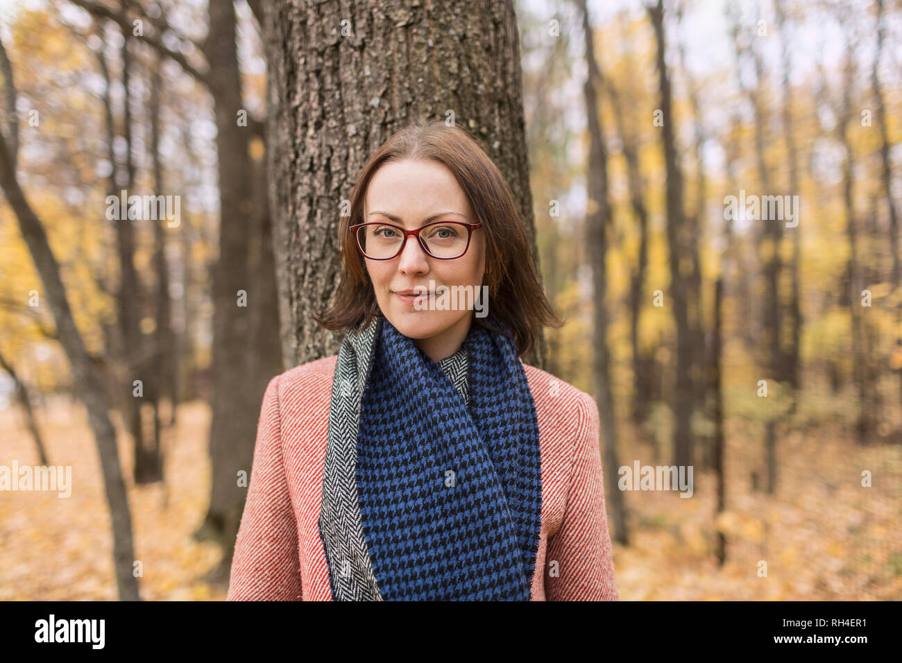 Ritratto di donna confida in una sciarpa in piedi contro Albero in autunno park Foto Stock
