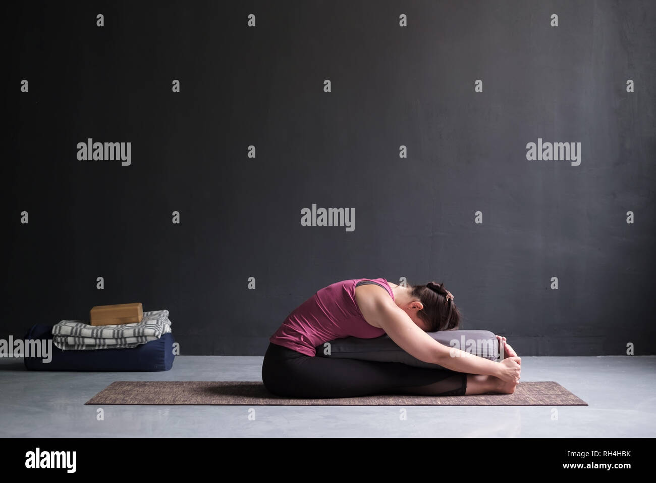 Donna pratica lo yoga, facendo seduti piegare in avanti pone, utilizzando il piano di appoggio. Foto Stock