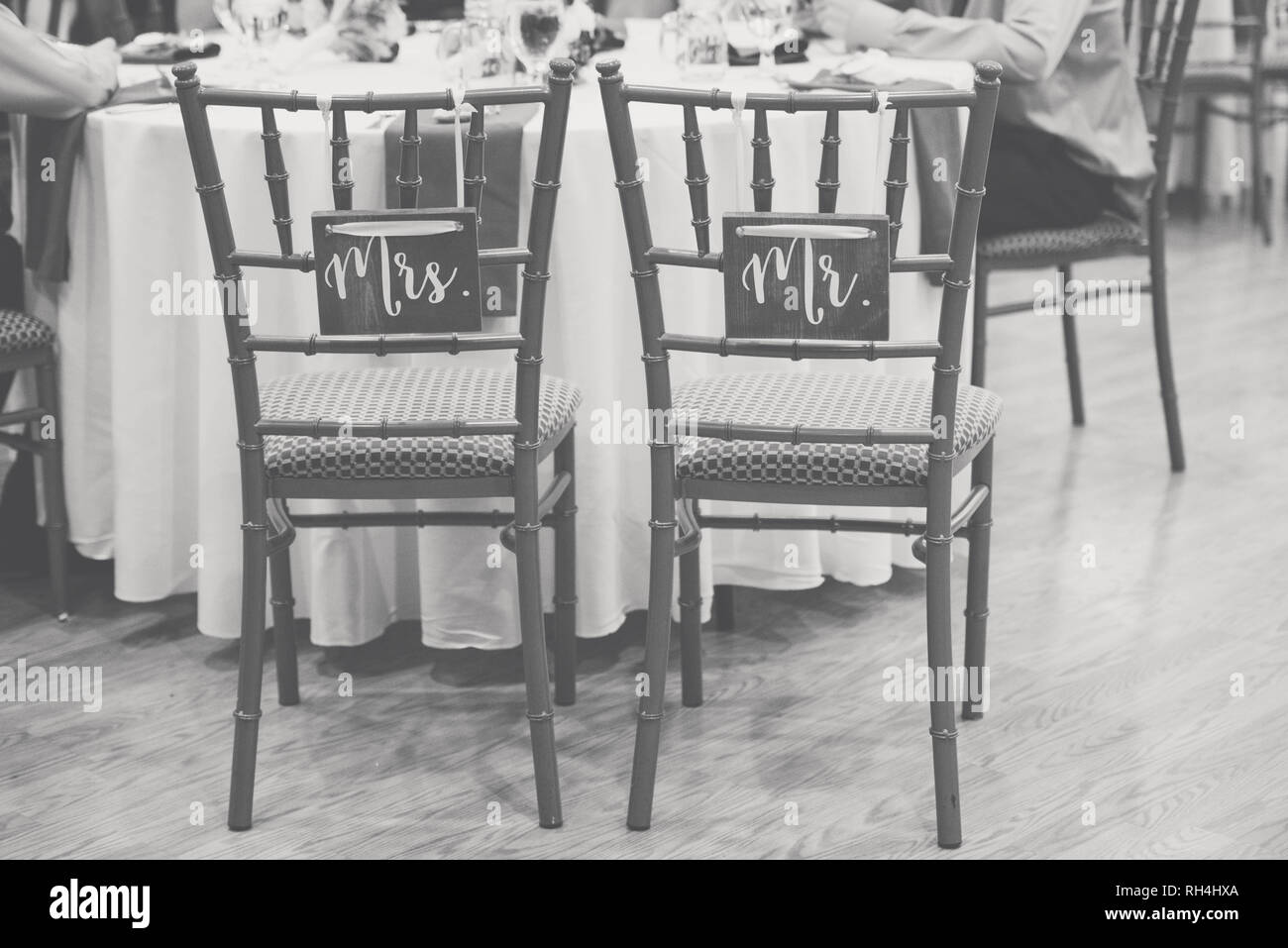 Sig. & Sig.ra Rustic cartelli in legno sulle sedie di sposa e di stanza a un ricevimento di nozze in una sala di catering immagine in bianco e nero Foto Stock