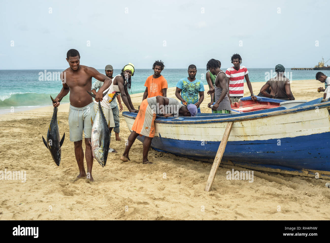 Capo Verde Isola di Maio: i pescatori di ritorno da un viaggio di pesca,  sulla spiaggia di Porto Ingles (Vila do Maio). Lo scarico del pesce: uomo  con due pesci nel suo