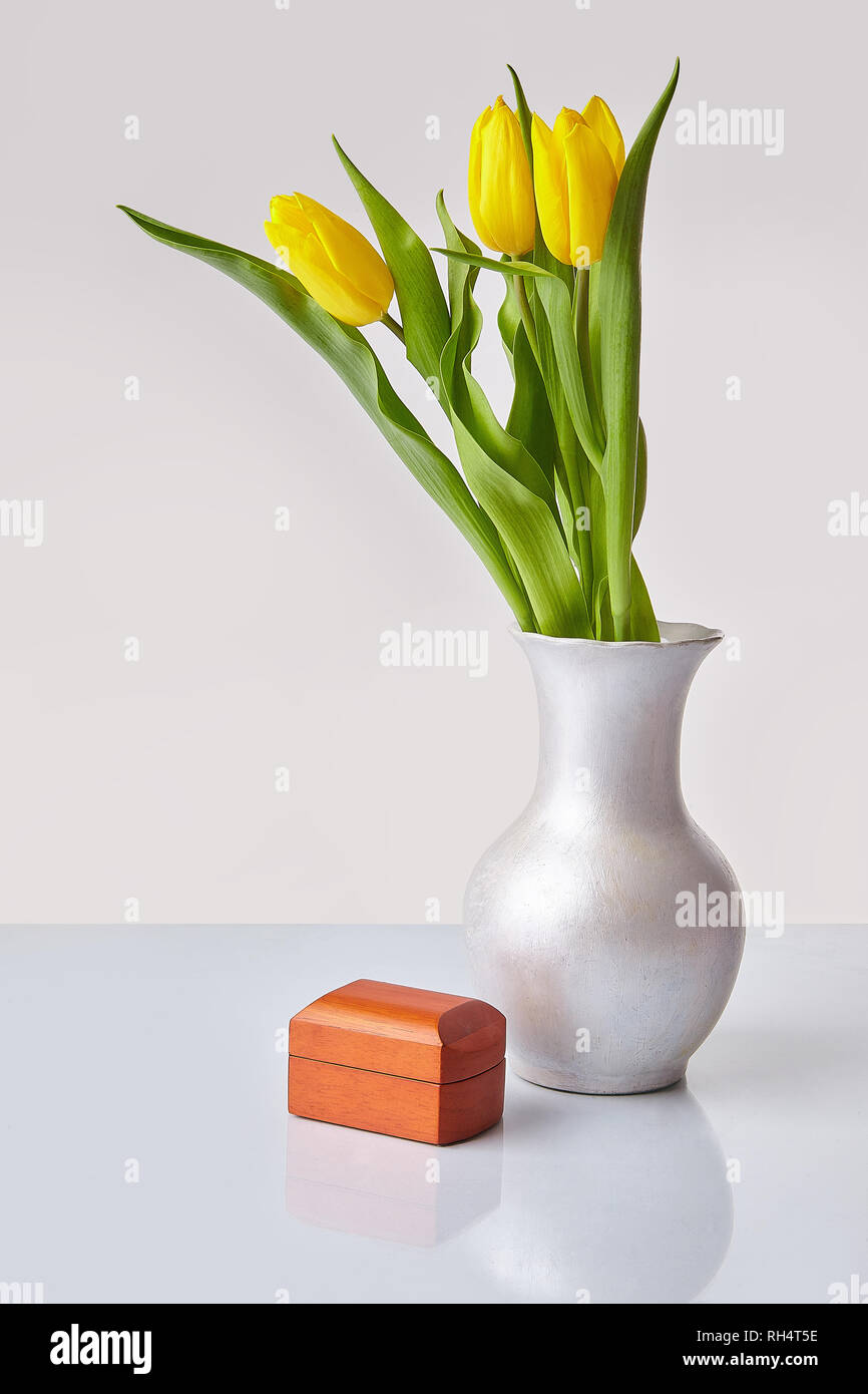 Fiori di Primavera. Tulipani gialli mazzo di fiori in un vaso con un di legno confezione regalo. Spazio per il testo. Sfondo bianco. Foto Stock