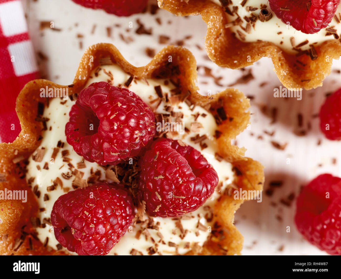Il Brandy snap cesti riempiti con aroma di limone e crema guarnita con lamponi e scaglie di cioccolato Foto Stock