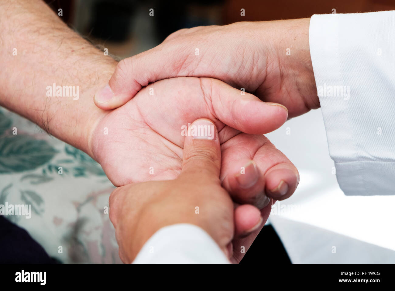 Primo piano di un uomo caucasico, in camice bianco, muovendo la mano di un senior caucasica uomo paziente, a casa sua o in una casa di cura Foto Stock
