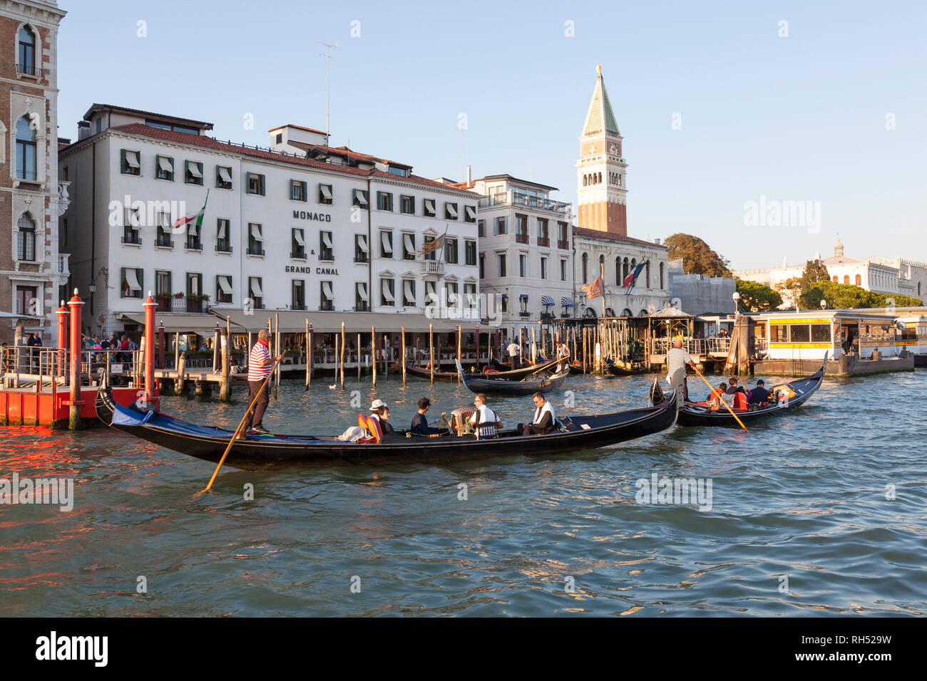 Turisti che si godono una serata serenata in gondola, Grand Canal, San Marco, Venezia, Veneto, Italia con un lettore di formare fisarmonica passando il Monaco Hotel Foto Stock