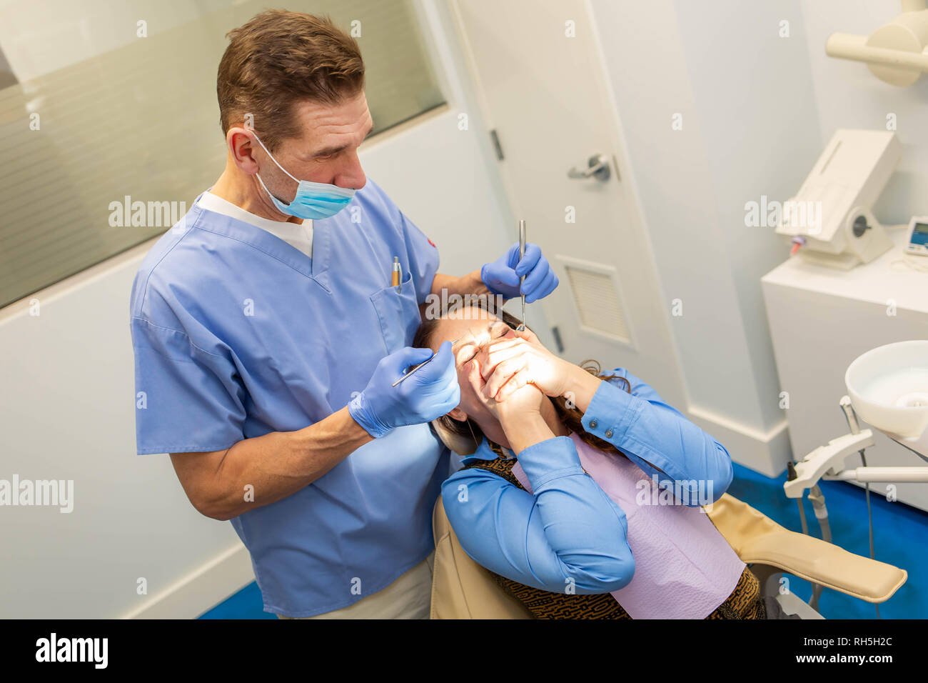 Dentista esegue il trattamento dei denti con la paura del paziente femmina chiusa la bocca con le mani Foto Stock