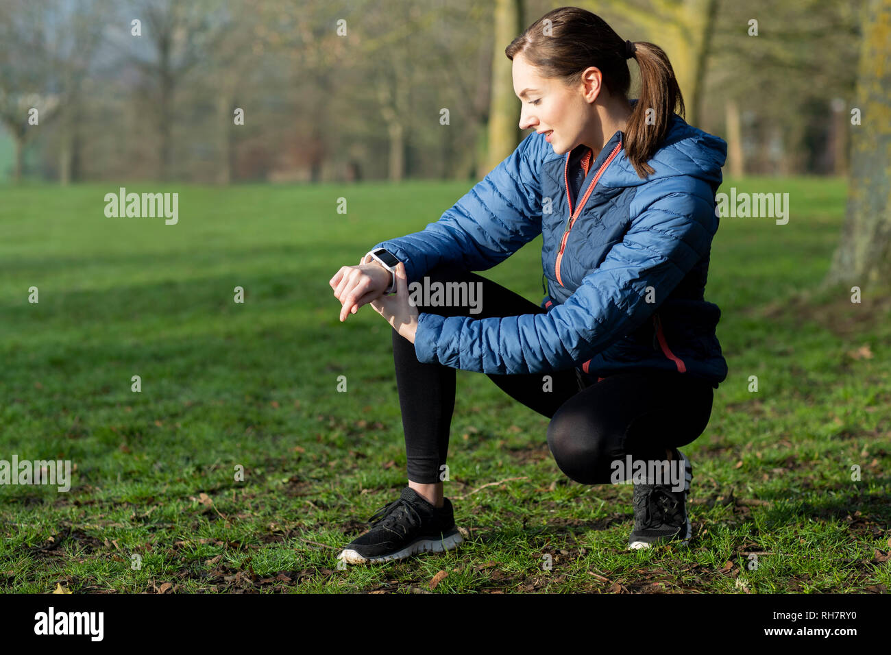 Donna che esercitano in Winter Park guardando il tracker di attività su Smart Watch Foto Stock