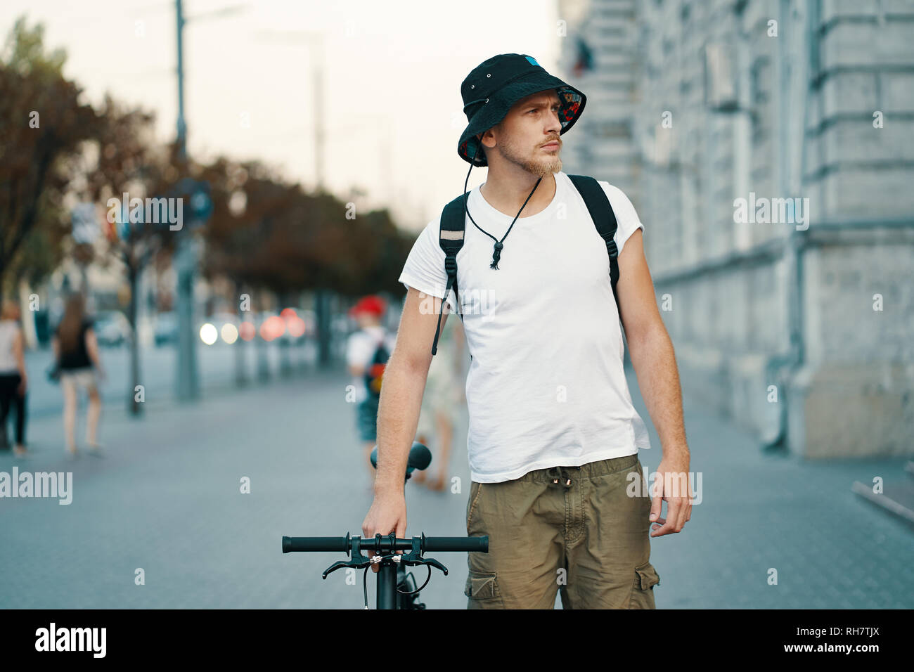 Un uomo in sella a una moto in una vecchia città europea all'esterno. Lo stile di vita, trasporti ecologici, persone concetto. Foto Stock