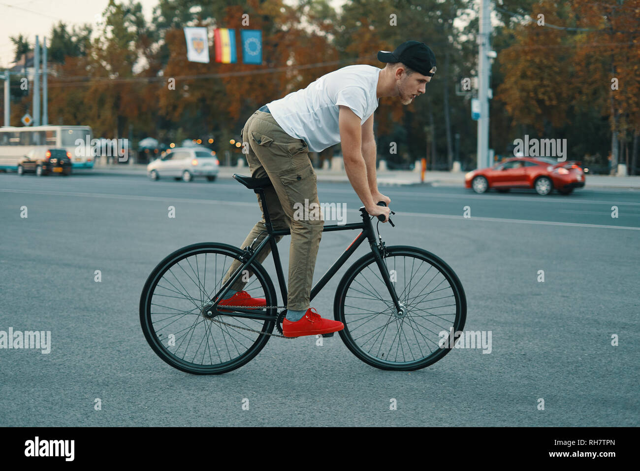 Vista laterale giovane uomo moderno ciclismo su un classico moto sulla strada della città. Copia dello spazio. Attivo e stile di vita ecologico concetto Foto Stock