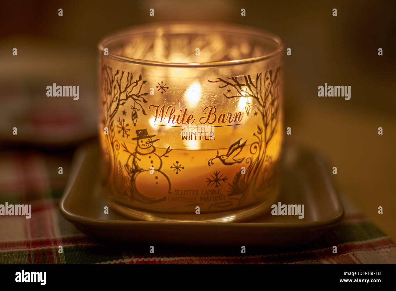 La candela profumata brucia con una luce calda su una sera d'inverno Foto Stock
