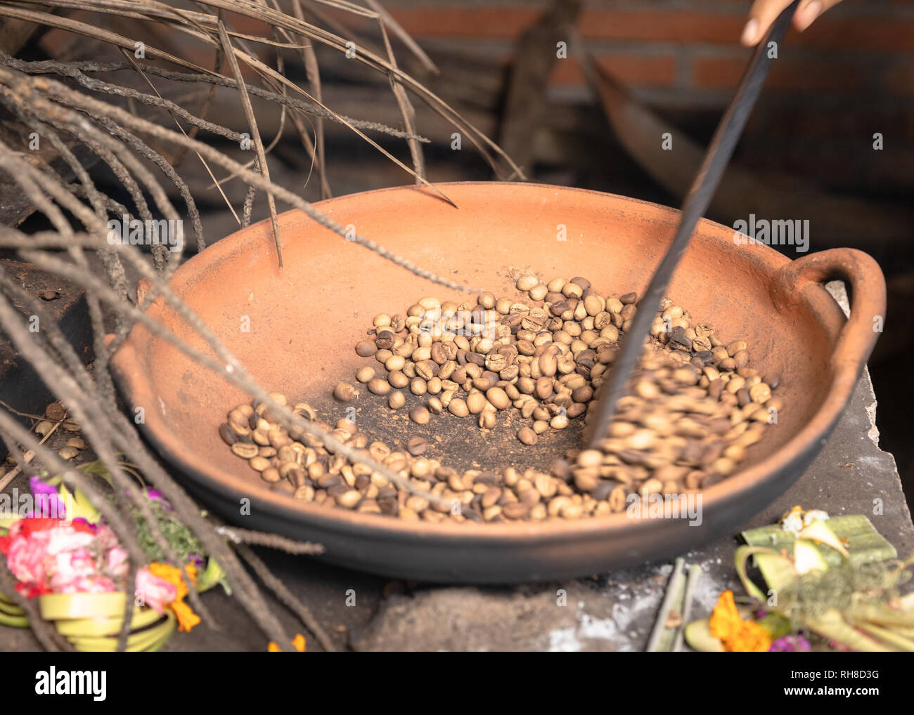 Tradizionali di chicchi di caffè La tostatura in una padella, la mano che regge un attrezzo di agitazione per spostare i fagioli. La tradizione di Bali. Motion Blur. Foto Stock