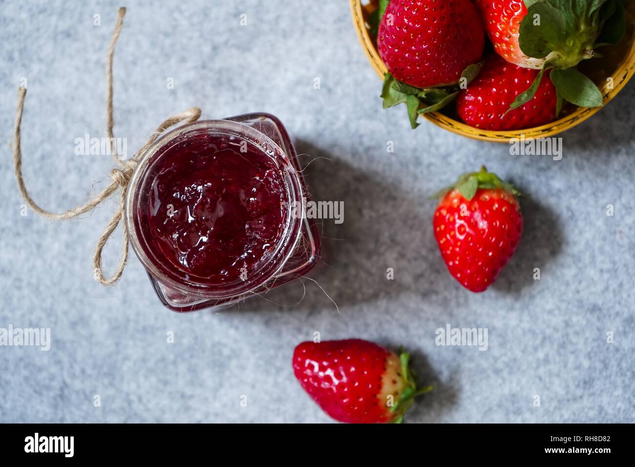 Confettura di fragole o di conservare in un vaso e strawberrieson lato cestello, il fuoco selettivo Foto Stock