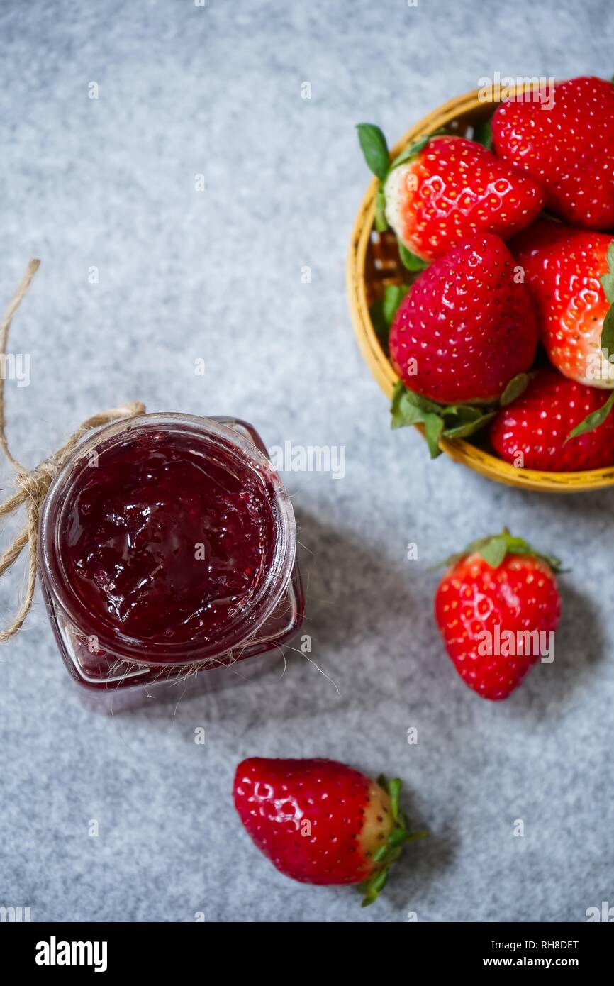 Confettura di fragole o di conservare in un vaso e strawberrieson lato cestello, il fuoco selettivo Foto Stock