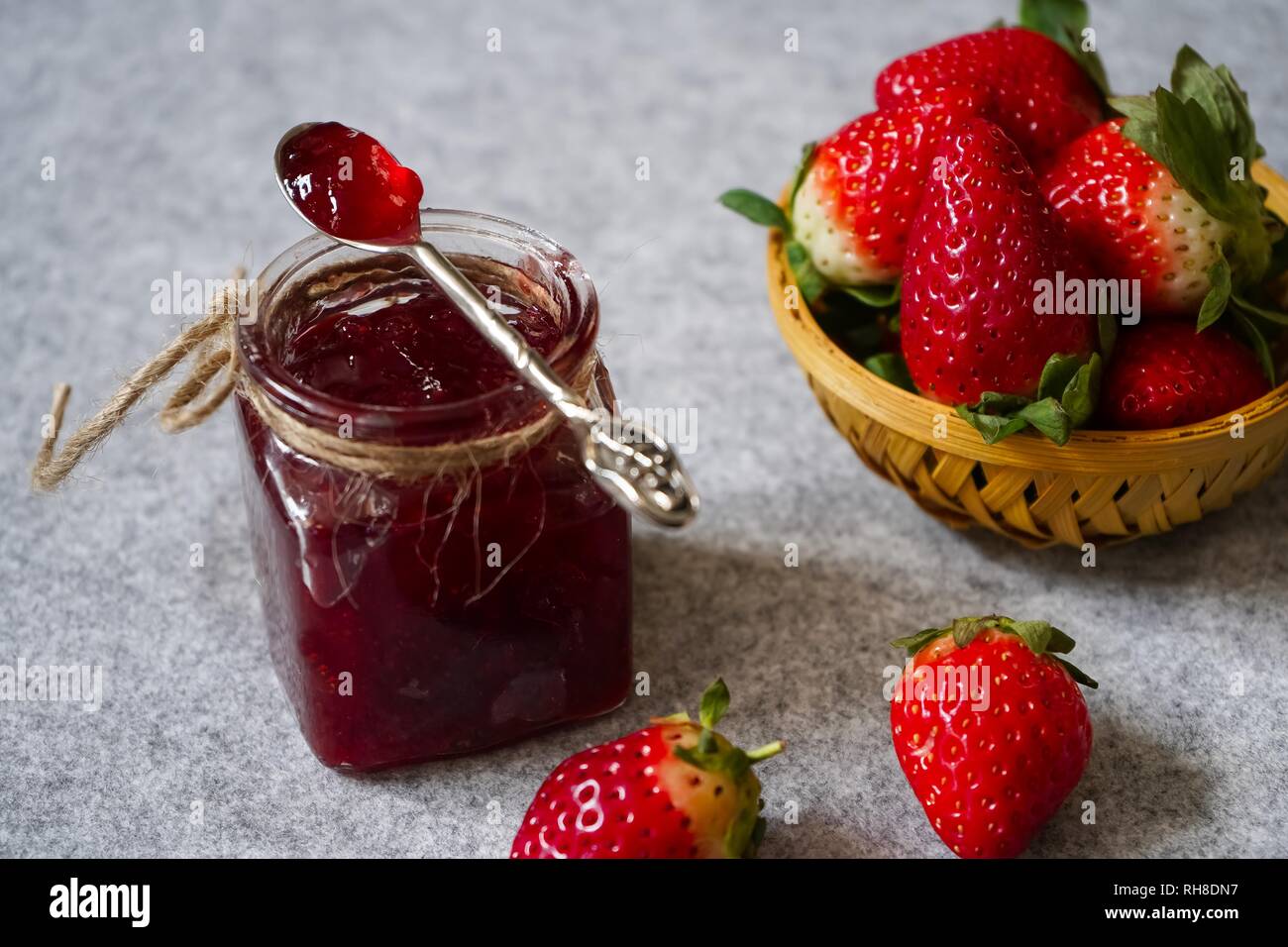 Confettura di fragole o di conservare in un vaso e strawberrieson lato cestello, il fuoco selettivo Foto Stock