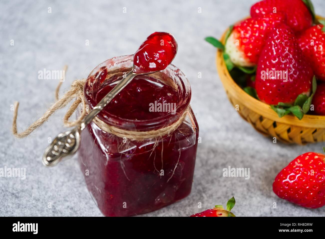 Confettura di fragole o di conservare in un vaso e strawberrieson lato cestello, il fuoco selettivo Foto Stock