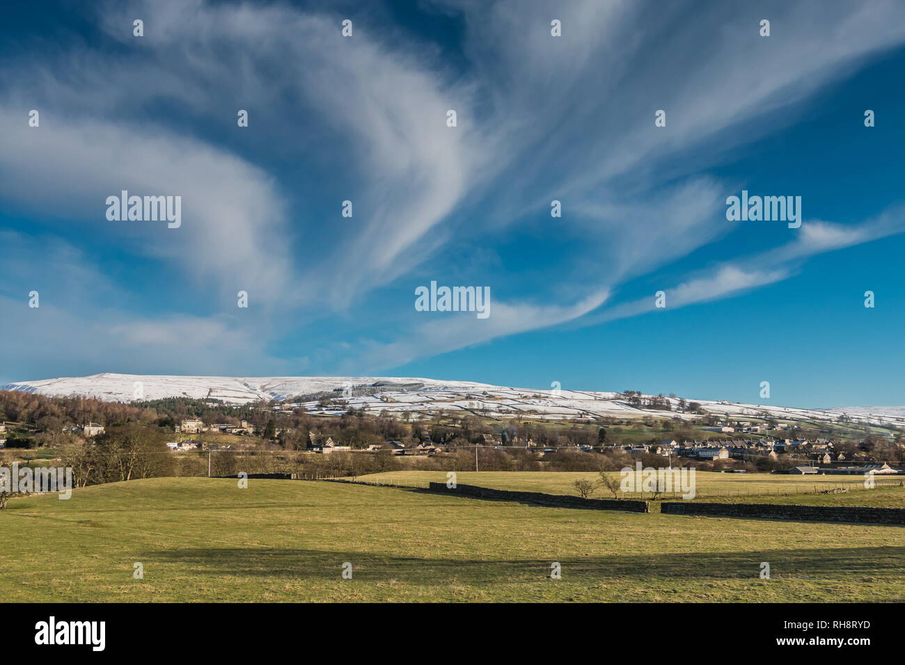 North Pennines AONB Paesaggio, Middleton in Teesdale con coperta di neve fells in background e una grande cirrus cloud overhead di formazione Foto Stock