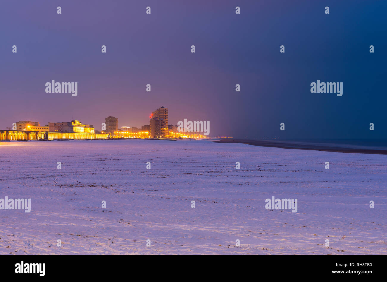 Paesaggio urbano di Ostenda (Ostenda) Città con spiaggia coperta di neve in inverno e Mare del Nord durante l'ora blu, Belgio. Foto Stock