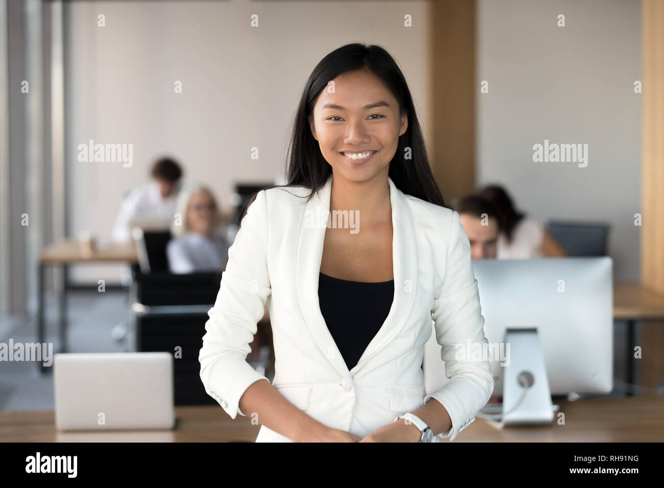 Sorridente giovane asian business donna che guarda la telecamera in ufficio Foto Stock