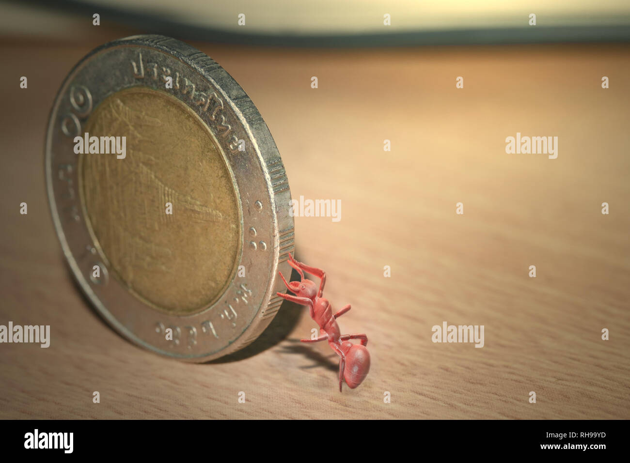 Vista del giocattolo ant spingendo le monete. Tono caldo. Foto Stock