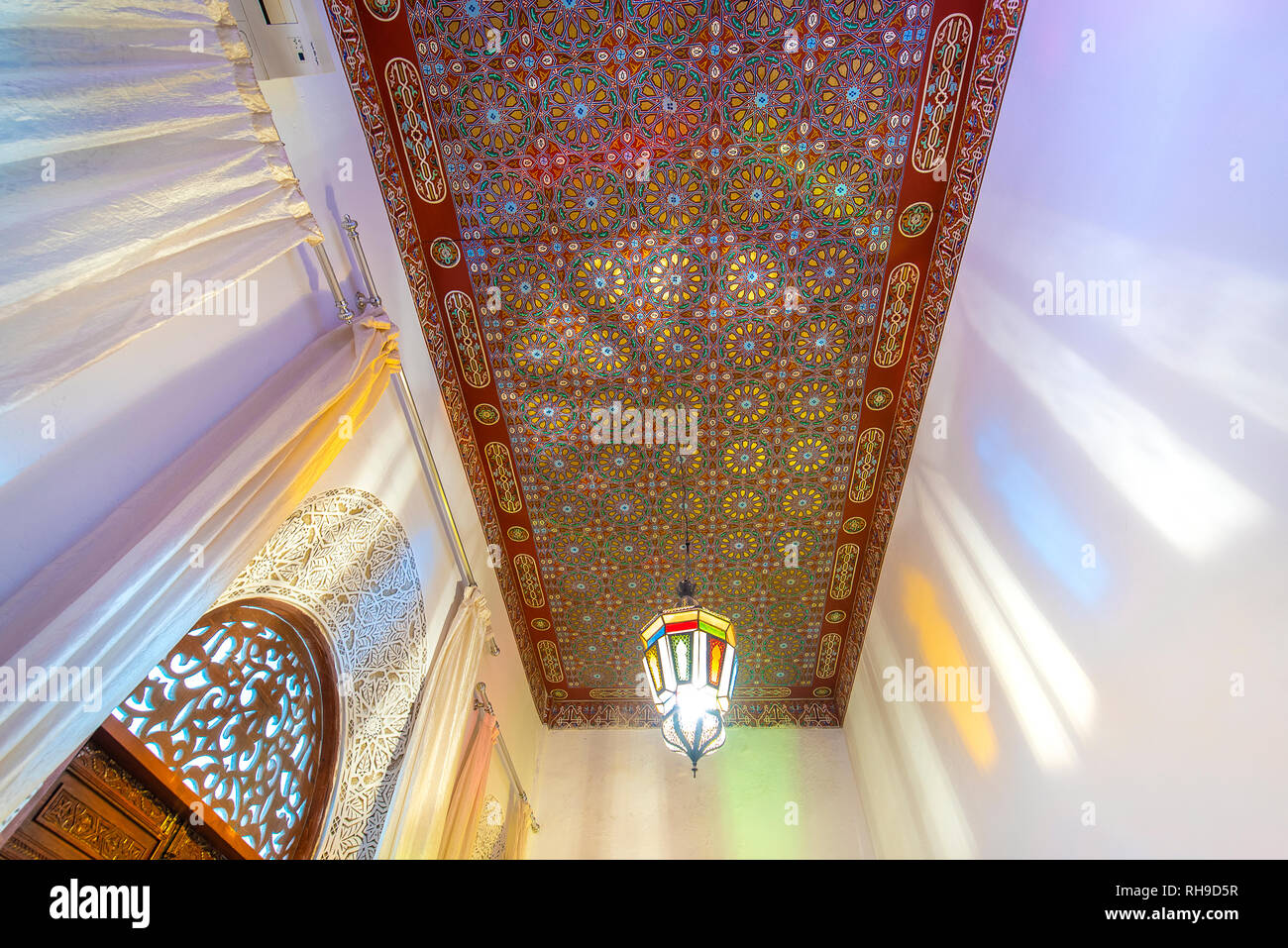 Cortile interno con pareti in piastrelle e pavimento di mosaico. Tradizionale e ornati arabesque colorate sculture di parete al di sopra di un arco nel riad marocchino . Foto Stock
