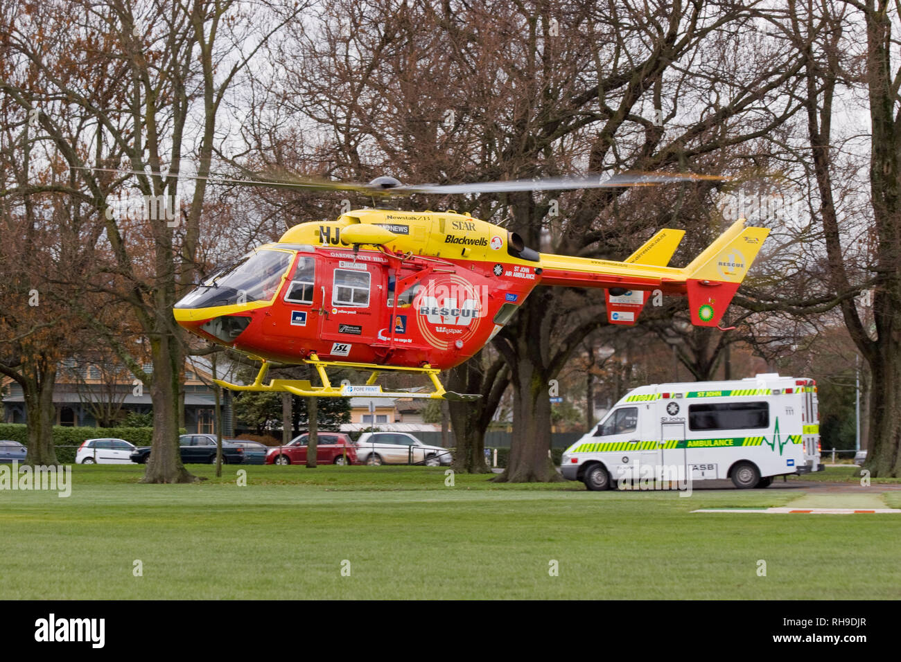 Un MBB/Kawasaki BK 117 Salvataggio in elicottero incontra un St John Ambulance in un parco locale per il trasferimento di un paziente in ospedale di Christchurch, Nuova Zelanda Foto Stock