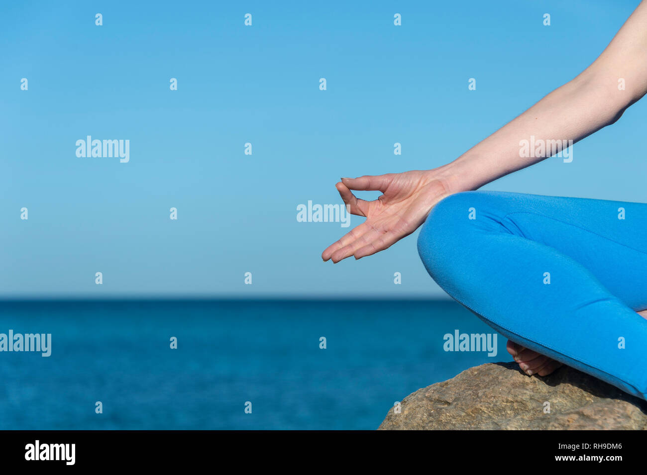 In prossimità di una donna meditando sul mare con un cielo blu Foto Stock