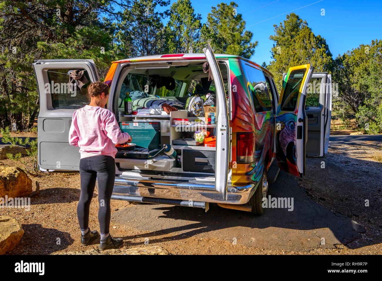 Giovane donna la cottura al fornello a gas di un camping Van, Camper, camping, RV, Mather campeggio, il Parco Nazionale del Grand Canyon Foto Stock