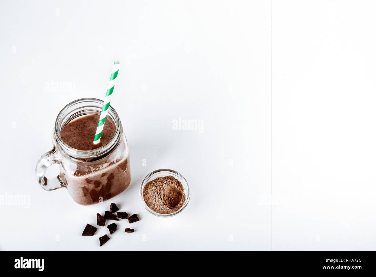 Un bicchiere di proteina con il cacao in polvere e su sfondo bianco Foto Stock