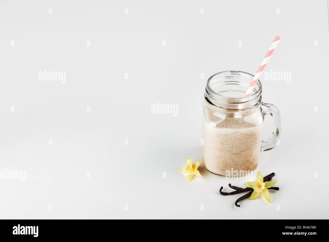 Cocktail di proteine con il latte e la vaniglia in un vasetto di vetro con cannucce. Nutrizione Sportiva Foto Stock