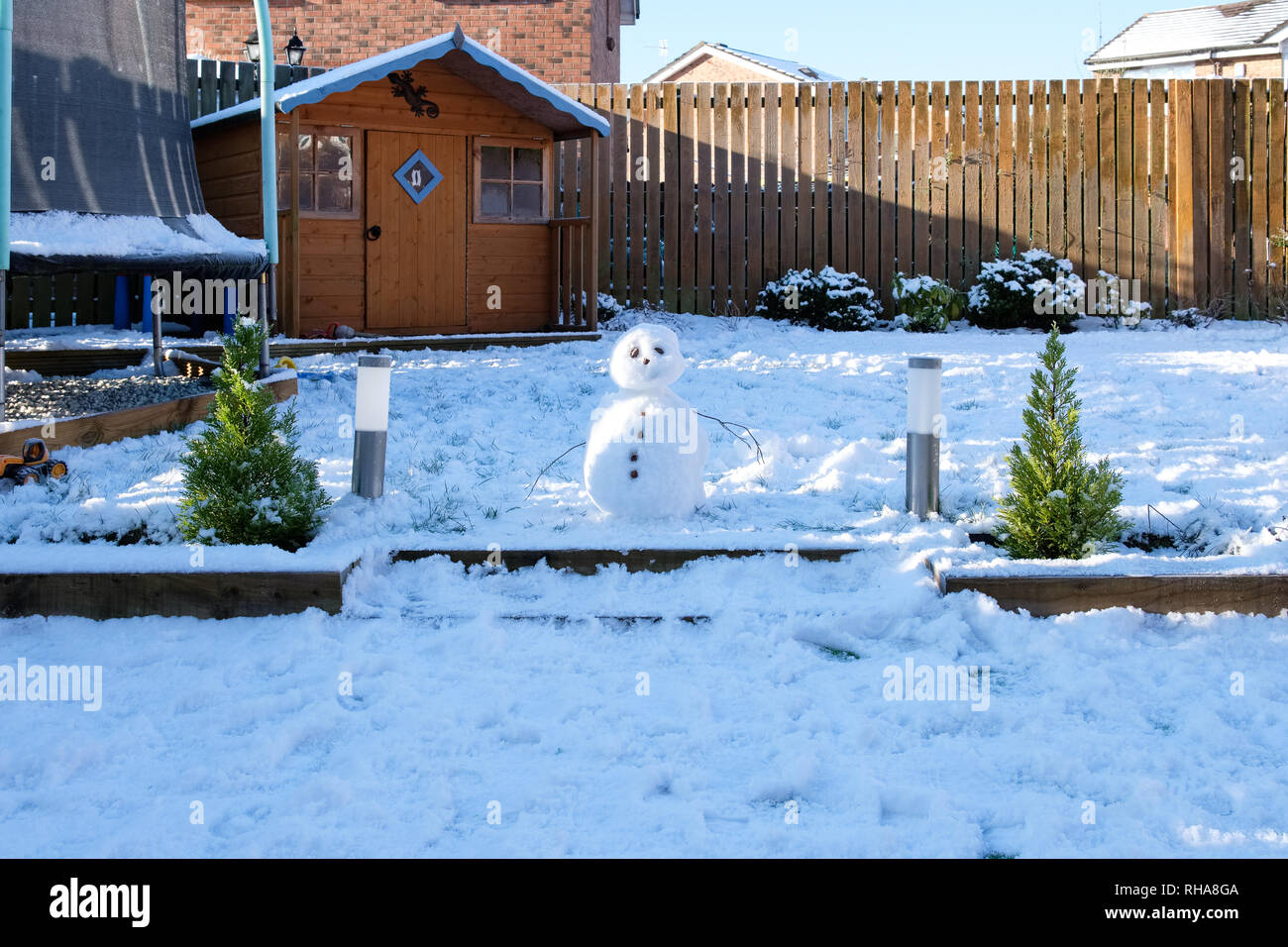 Piccolo pupazzo di neve in una scozzese giardino sul retro con ramoscelli di armi e di impostare in un giardino moderno in un snowie Scozia. Foto Stock
