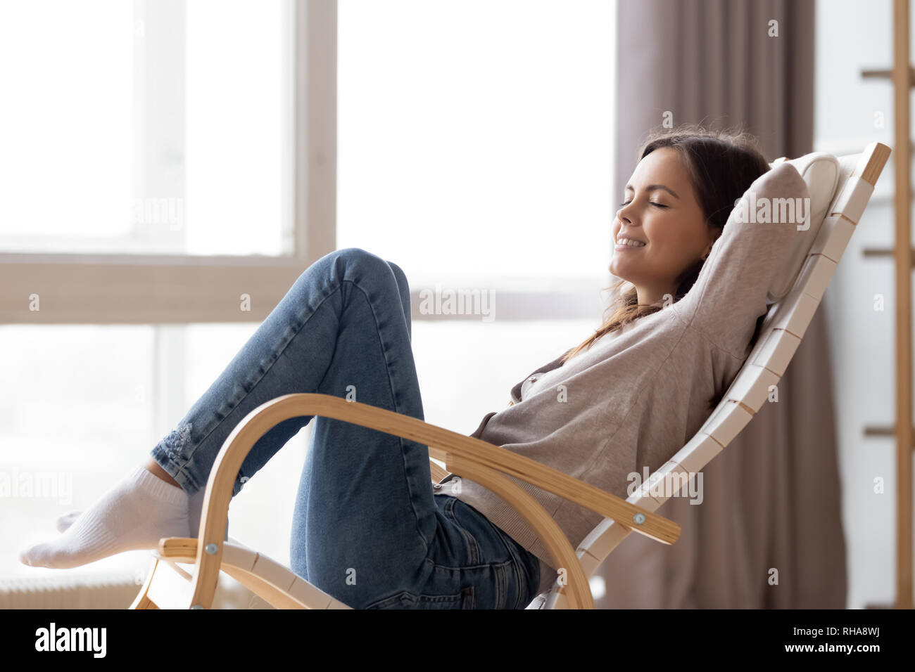 Rilassata calma giovane donna seduta relax nel confortevole sedia a dondolo Foto Stock