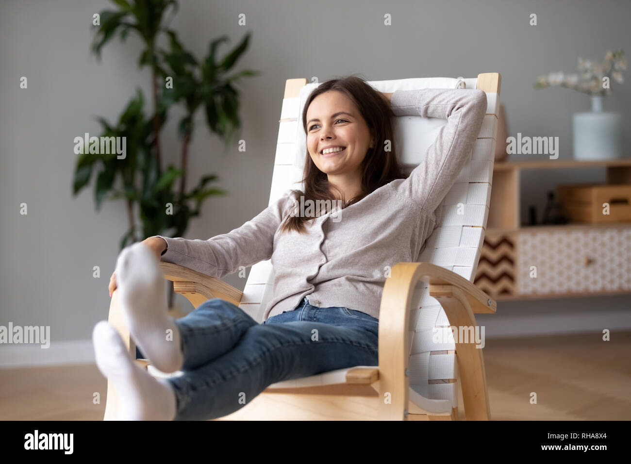 Sorridenti ragazza rilassarsi su confortevoli in legno sedia a dondolo Foto Stock