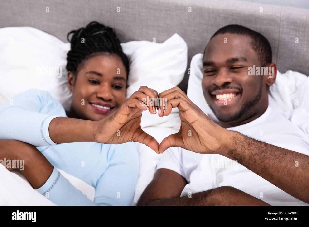 Felice coppia africana giacente sul letto messa a forma di cuore Foto Stock