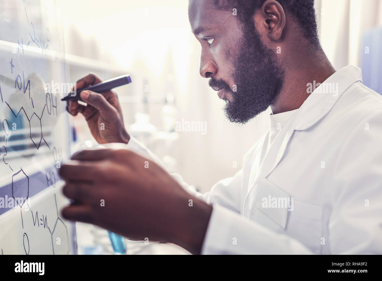 Seriamente guardando giovane farmacista iscritto formula chimica Foto Stock