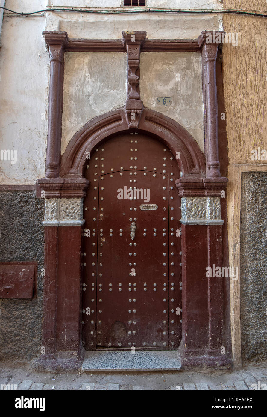 Tipico, vecchio, marrone intricate sculture, costellata, riad marocchino porta e porta-cornice e la vecchia casa in Marrakech, Marocco Foto Stock