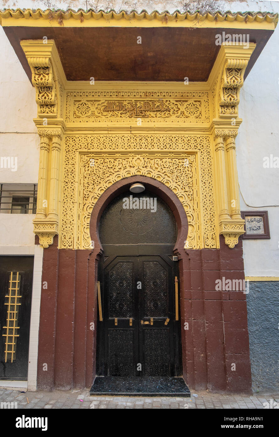 Tipico, vecchio, marrone intricate sculture, costellata, riad marocchino porta e porta-cornice e la vecchia casa in Marrakech, Marocco Foto Stock