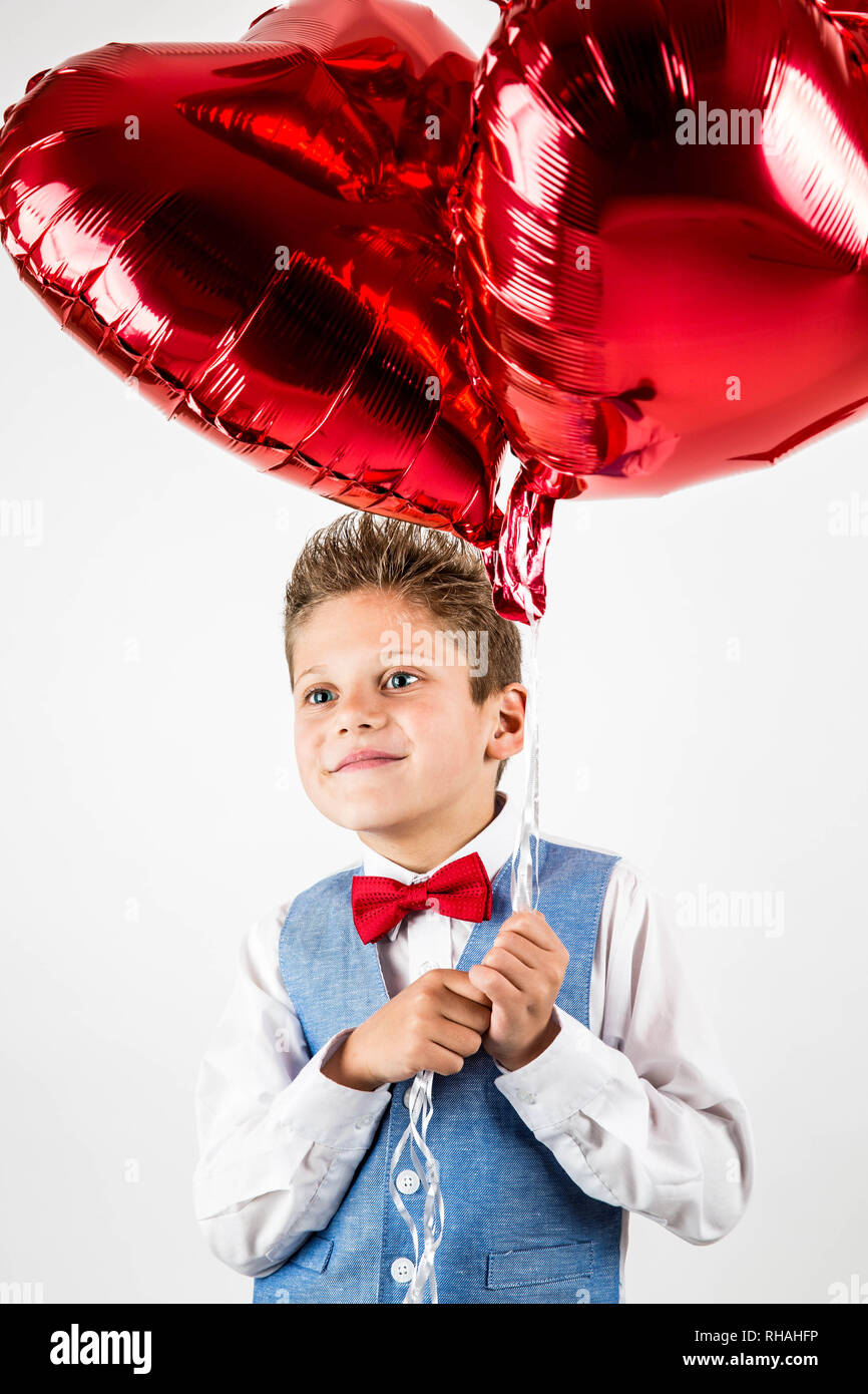 Il giorno di San Valentino. Gentiluomo bello ragazzo con giubbotto blu, cravatta rossa, rose rosse benna e palloncini rossi . Il giorno di San Valentino i ragazzi. Amore e amicizia . Foto Stock