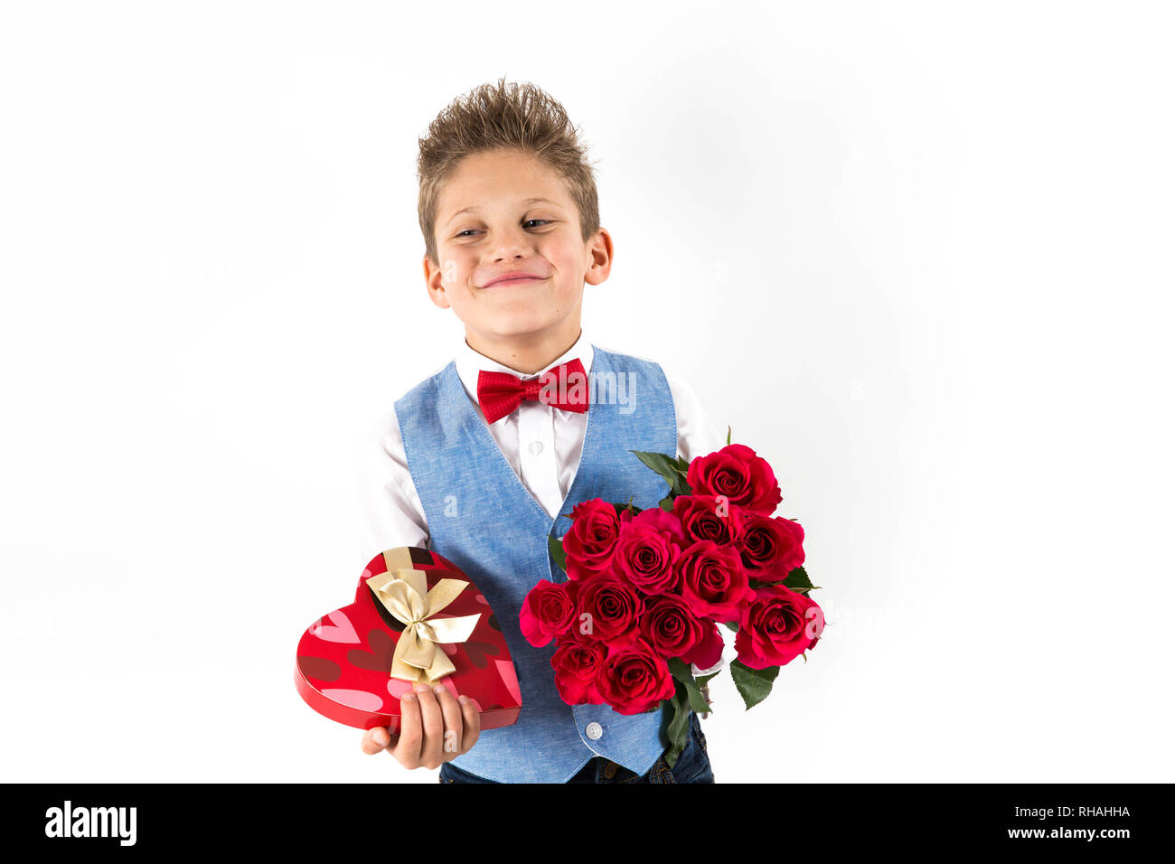 Gentleman ragazzo con giubbotto blu, rosso cravatta a farfalla, rose rosse benna e a forma di cuore scatola regalo. Il giorno di San Valentino i ragazzi. Amore e amicizia. Giornata della donna Foto Stock