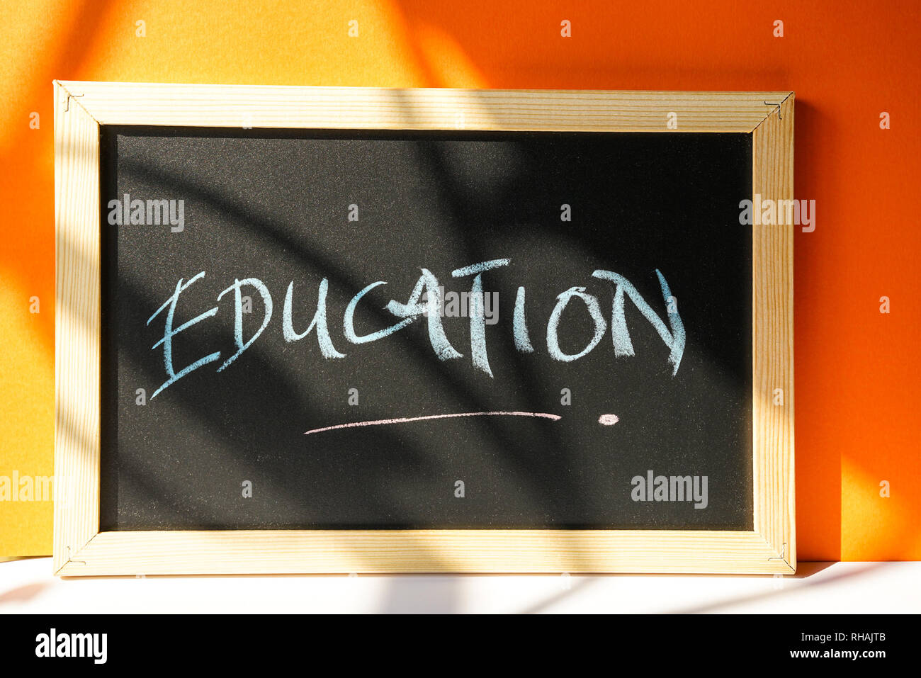 Lavagna nera su sfondo arancione con l'istruzione di testo scritto in Chalk Foto Stock