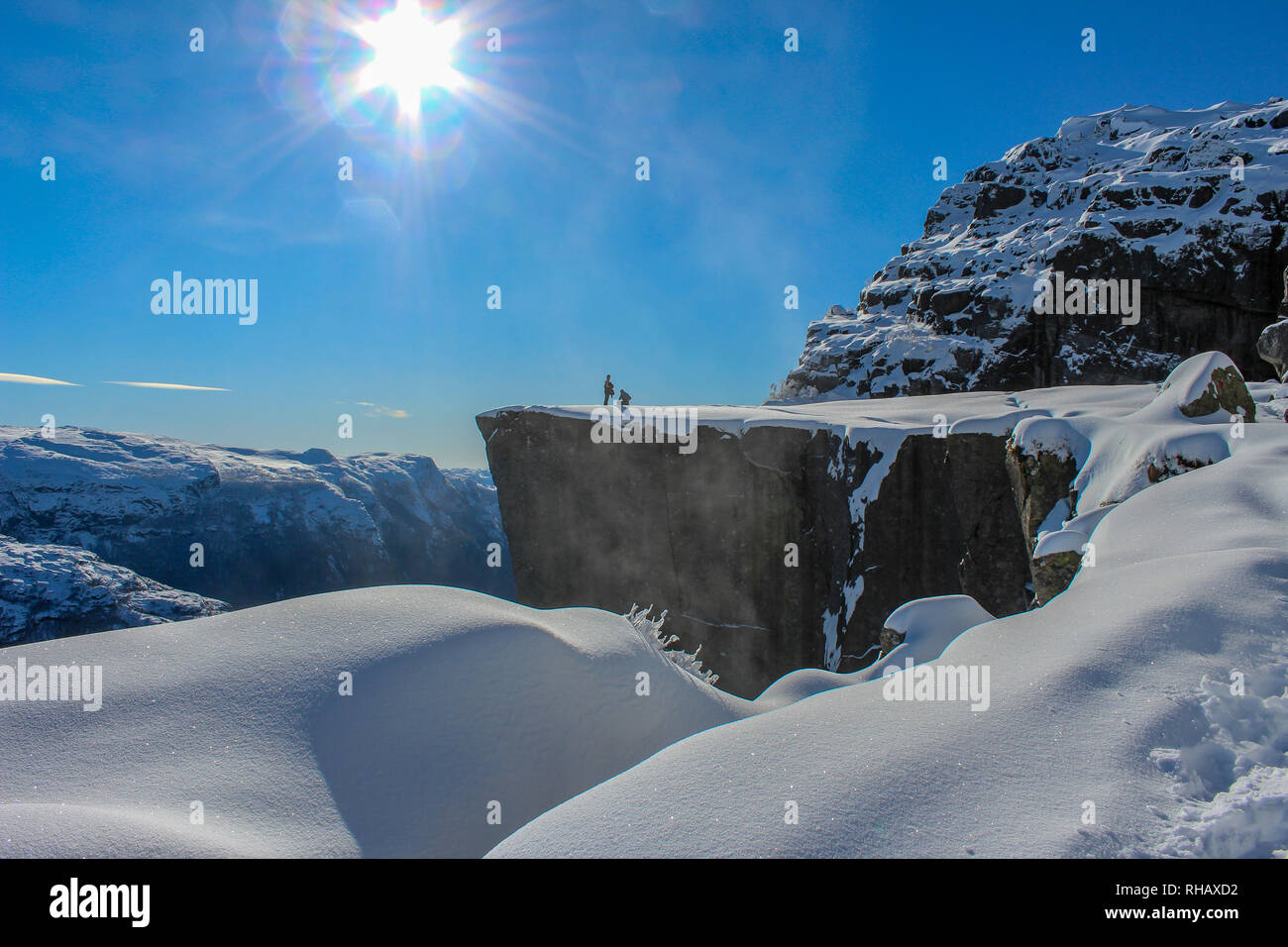 Due persone per godersi il sole sul Prekestolen in inverno, Stavanger, Norvegia Foto Stock