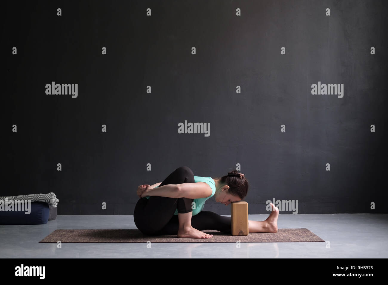 Giovane donna a praticare Yoga asana amarichyasana in ambienti interni Foto Stock