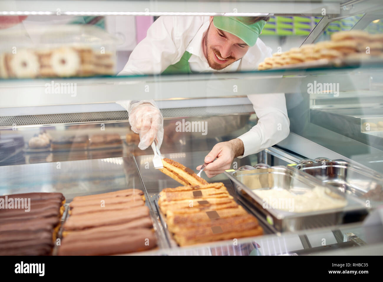 Lavoratore da forno molto attentamente tenendo la Torta di biscotti da vetrina Foto Stock