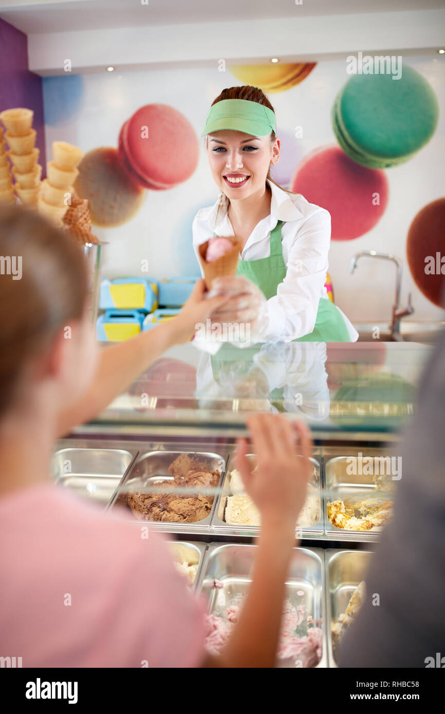 Tipo commessa in pasticceria store dà gelato alla ragazza Foto Stock