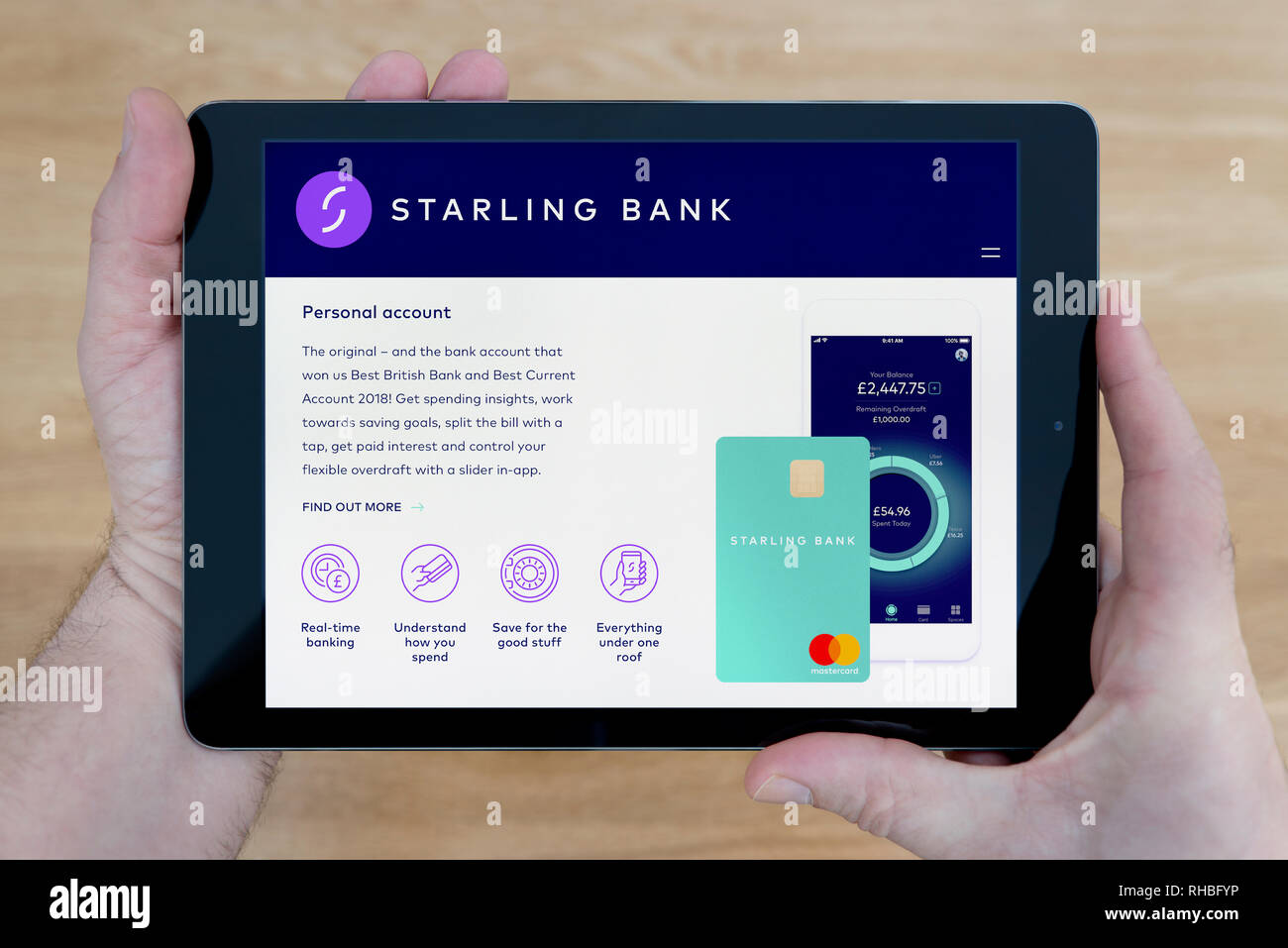 Un uomo guarda alla banca di Starling sito sul suo iPad dispositivo tablet,  sparato contro un tavolo di legno top sfondo (solo uso editoriale Foto  stock - Alamy