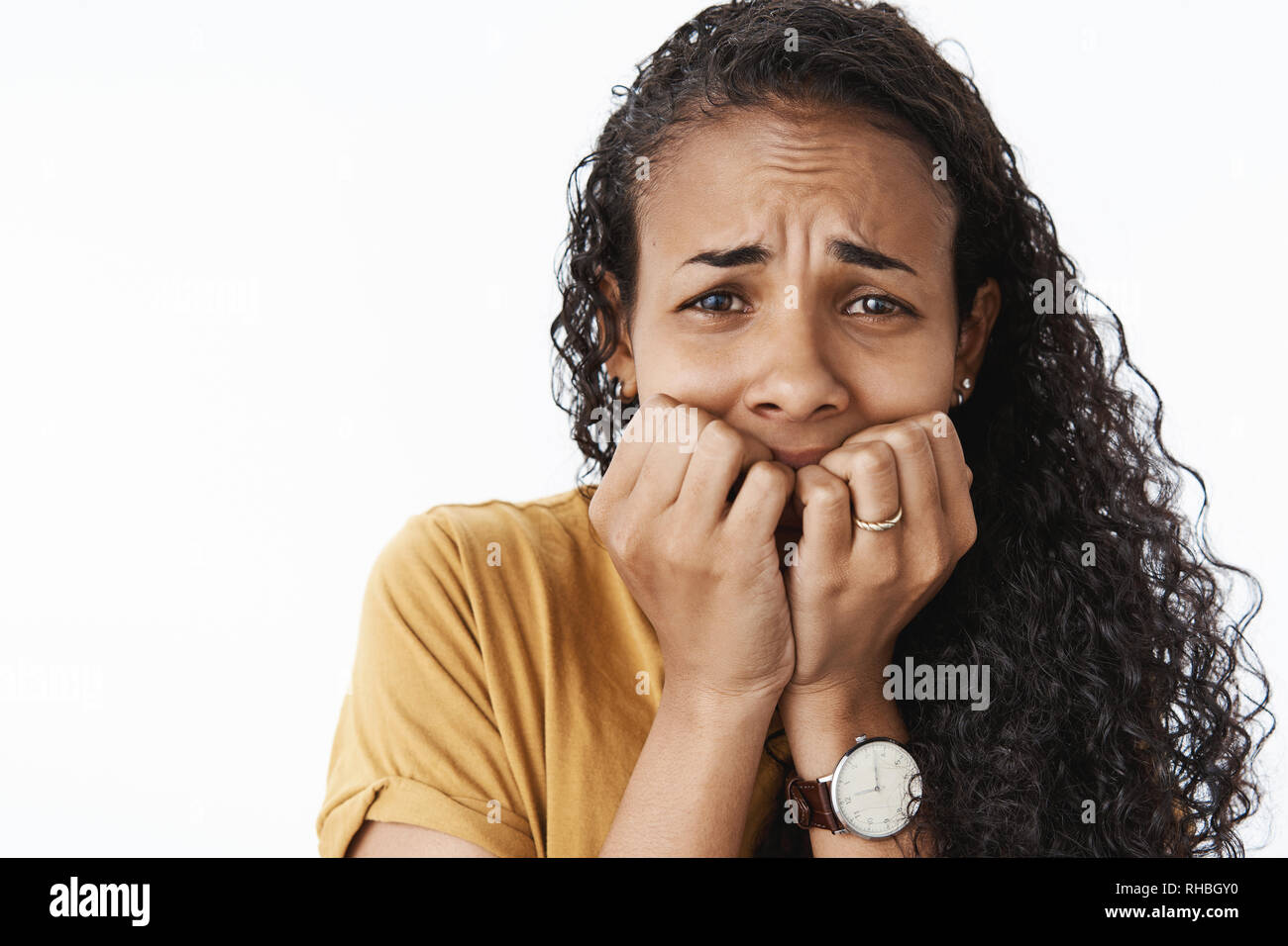 Close-up shot di freaked-out sconvolto il pianto americano africano essendo la donna impaurita e tremante terrorizzata dalla paura di mordere le unghie e accigliata Foto Stock