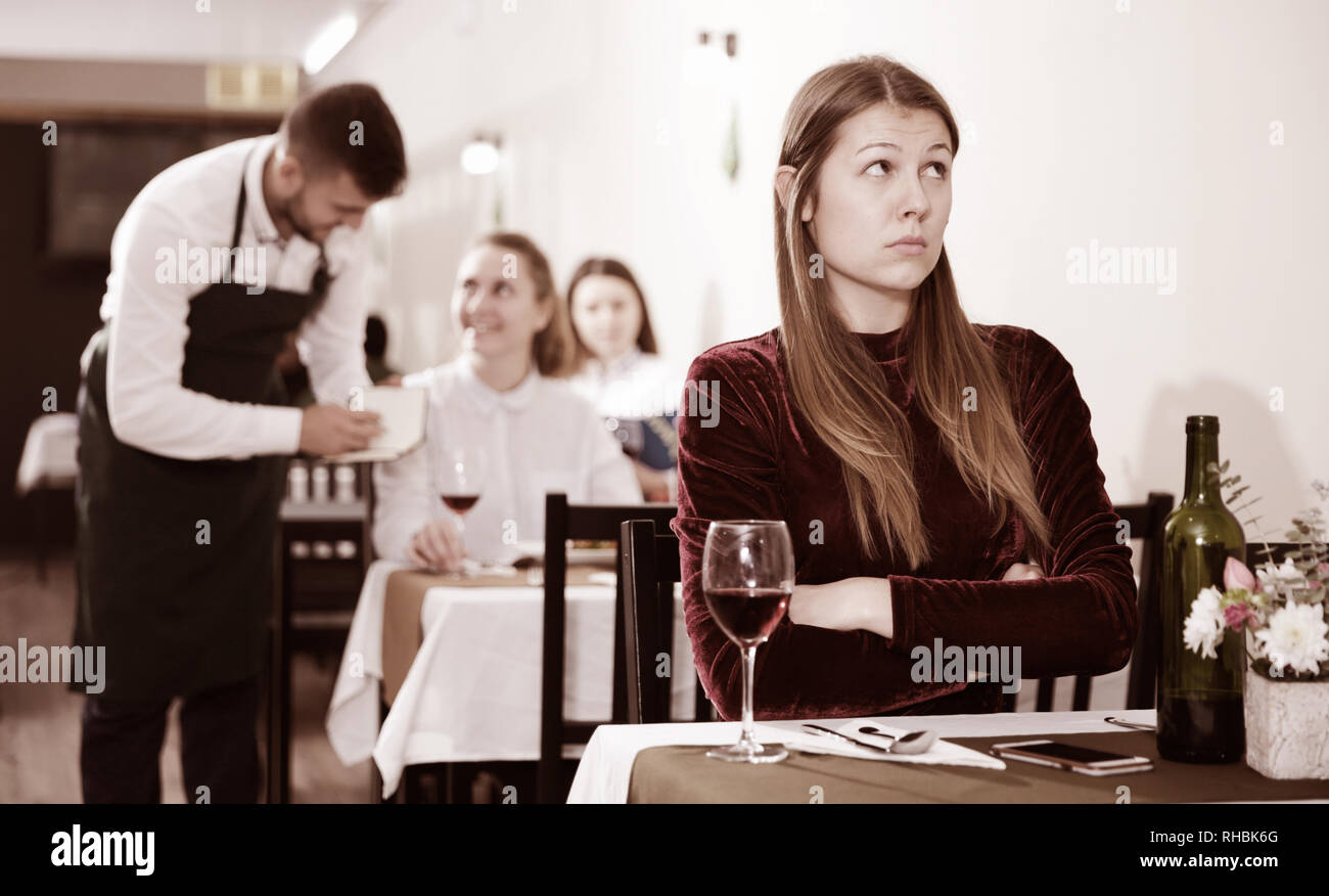 Triste è la donna a pranzo nel ristorante di lusso da soli indoor. Foto Stock