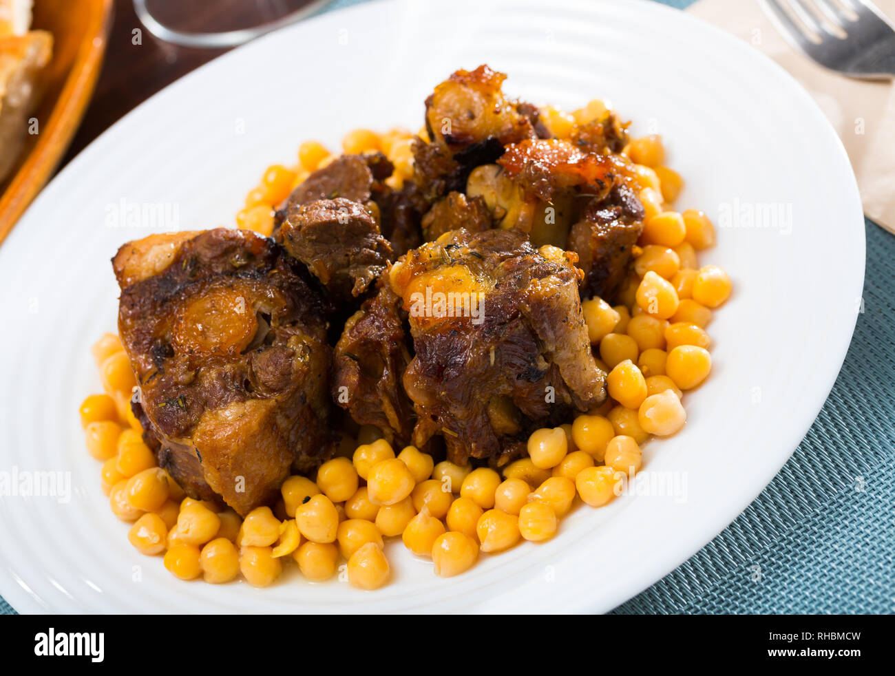 Brasati oxtails con ceci su una piastra bianca Foto Stock