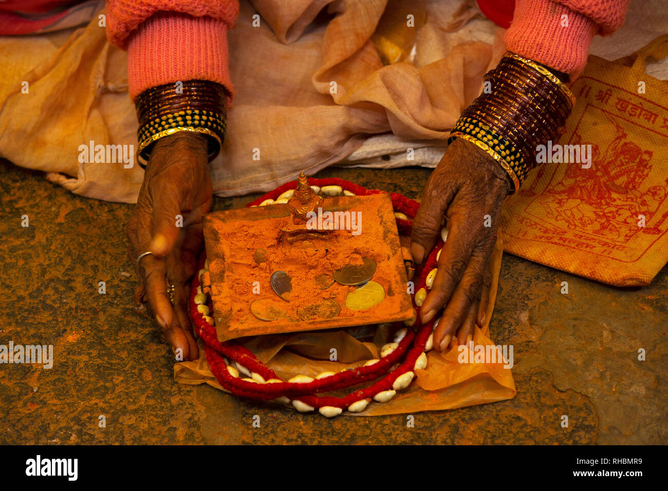 Donna con schiave e divinità con zafferano polvere colorata, Maharashtra, India Foto Stock