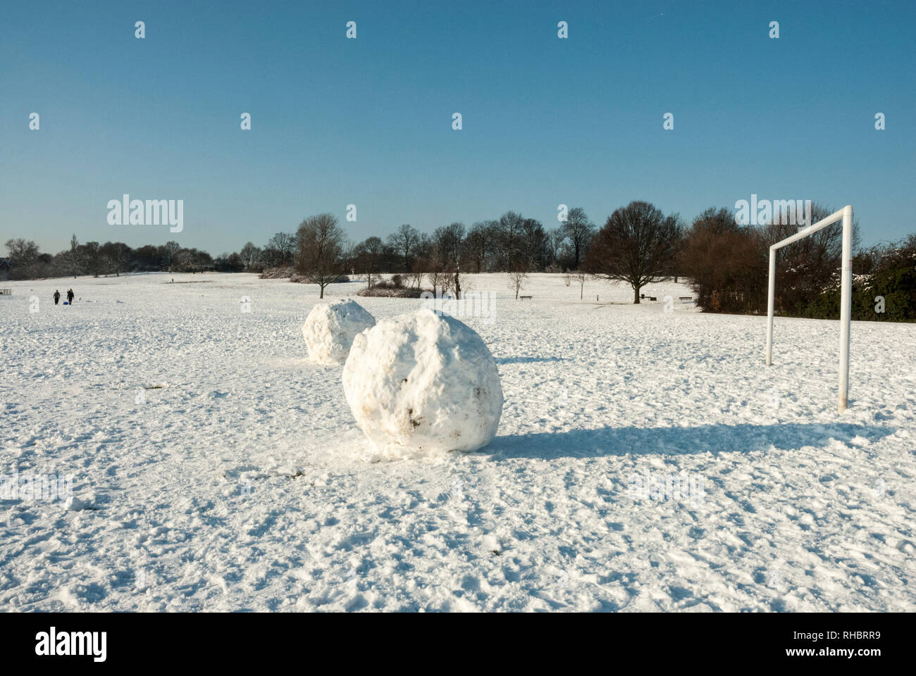 Snowballs enorme di fronte a un obiettivo aperto sulla coperta di neve sunny Hampstead Heath, giocare con il concetto di scala. Foto Stock