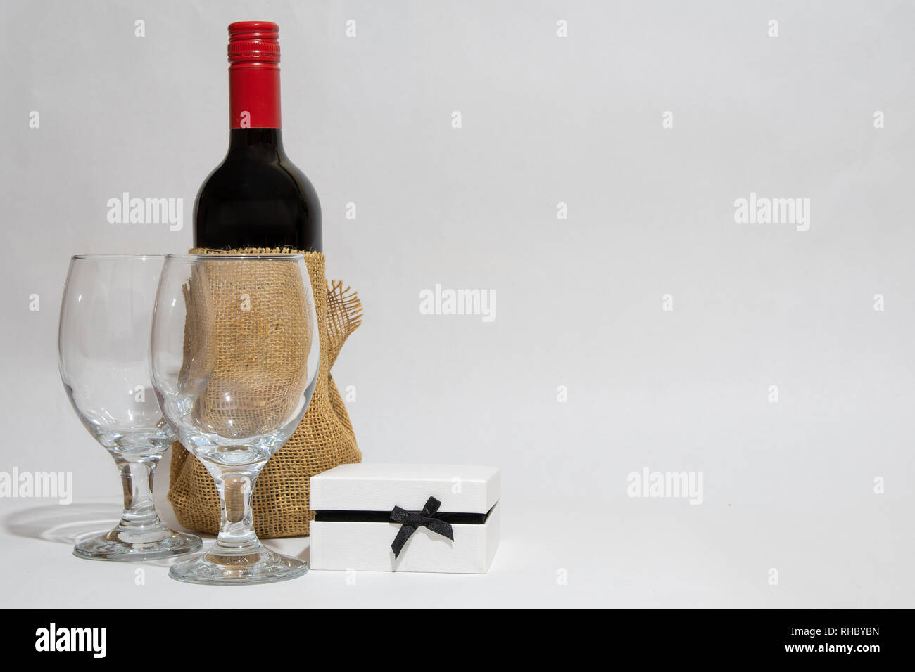 Bottiglia di vino rosso e due wineglasses e una scatola regalo bianca. Anniversario. La sua festa di compleanno. Il giorno di San Valentino. Foto Stock