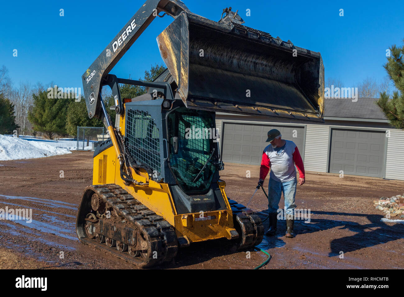 L'uomo Lavaggio off a John Deere per via del caricatore. Foto Stock